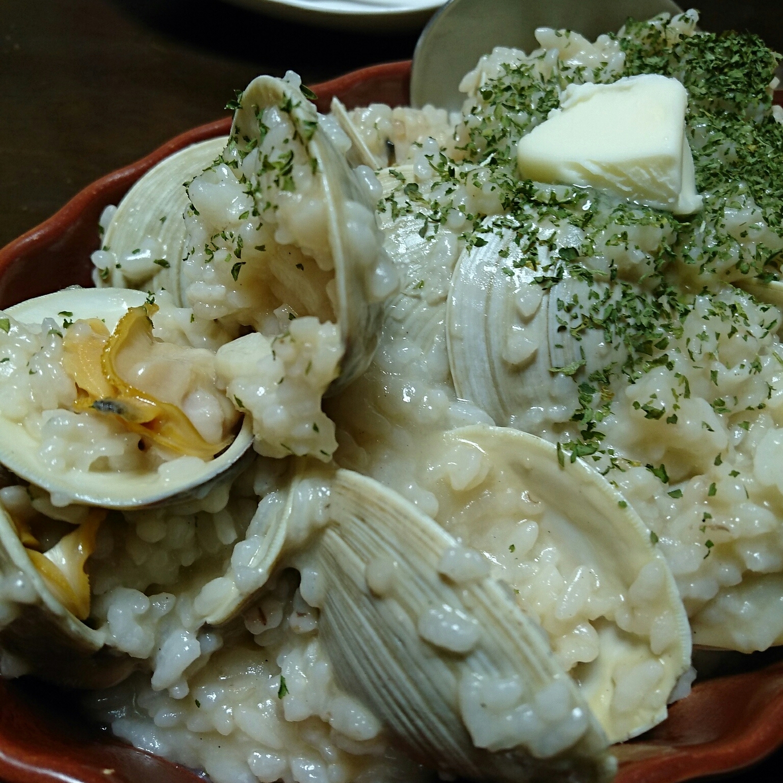 朱色の皿に盛り付けられたホンビノス貝のリゾット