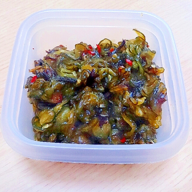 保存容器に入った輪切り唐辛子と塩こんぶ入りのきゅうりの佃煮を入れた白い容器