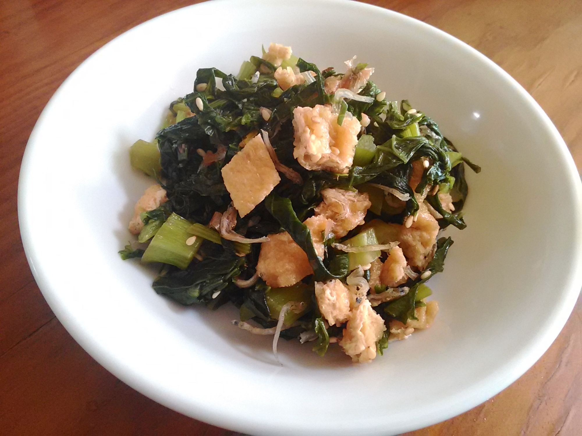 白い器に盛り付けられたかぶの葉と油揚げの炒め物